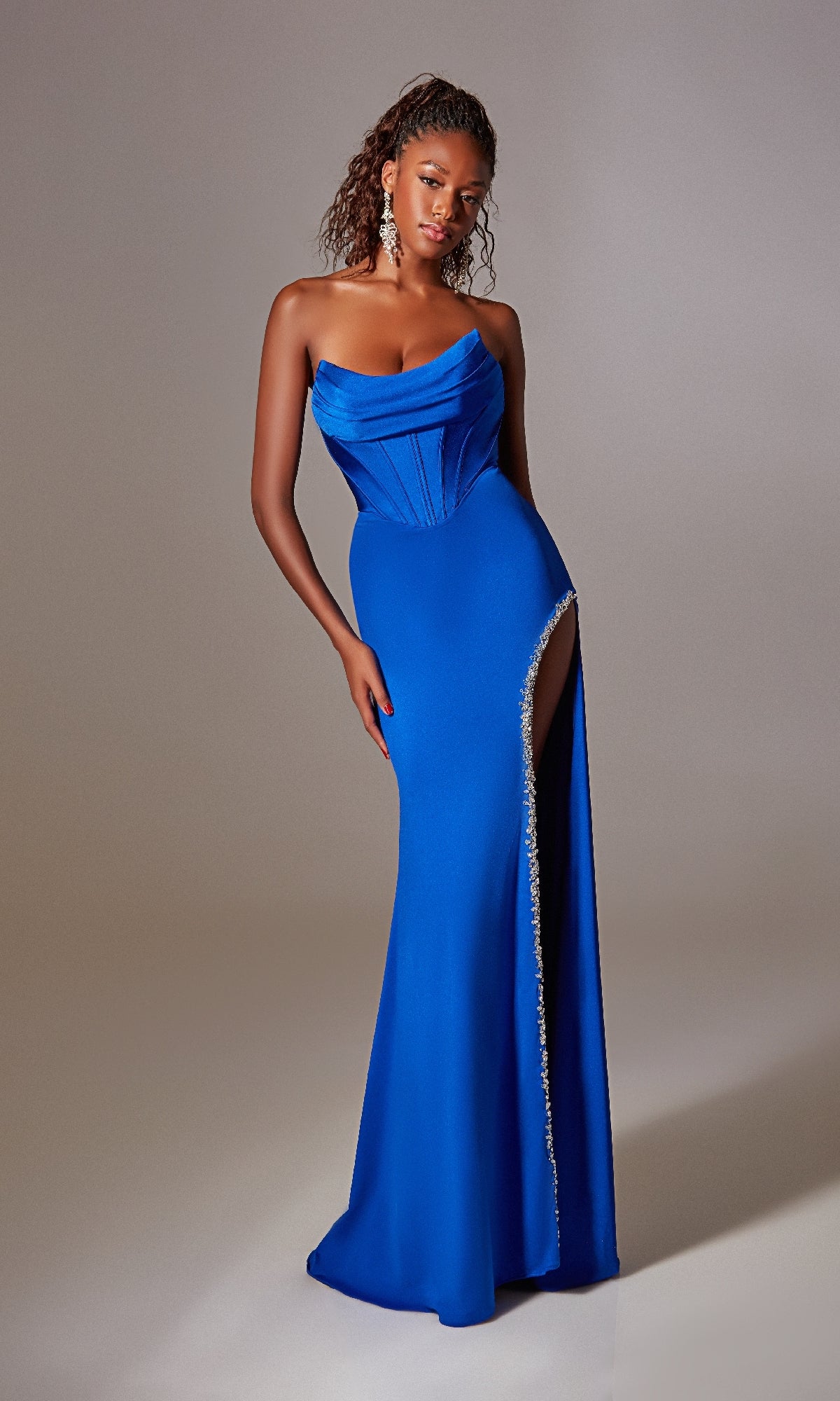 A woman wears the Strapless Long Prom Dress: Aerie Couture 249 in royal blue, featuring a corset waist and a rhinestone-trimmed side slit for sparkle.